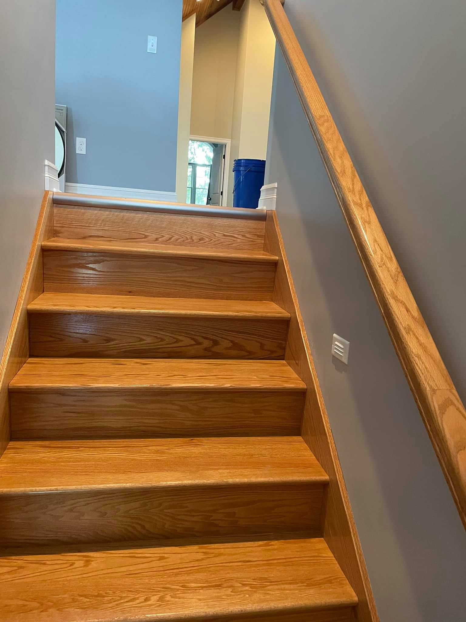 A wooden staircase with a wooden railing leading up to the second floor of a house.