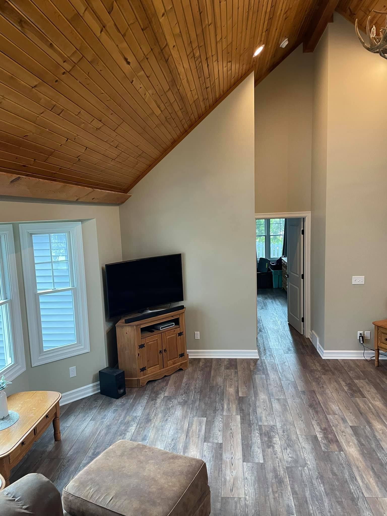 A living room with a vaulted ceiling and a flat screen tv.