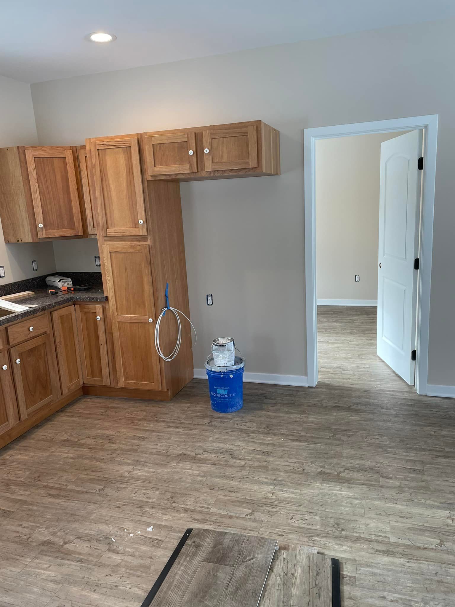 A kitchen with wooden cabinets and a blue bucket on the floor.