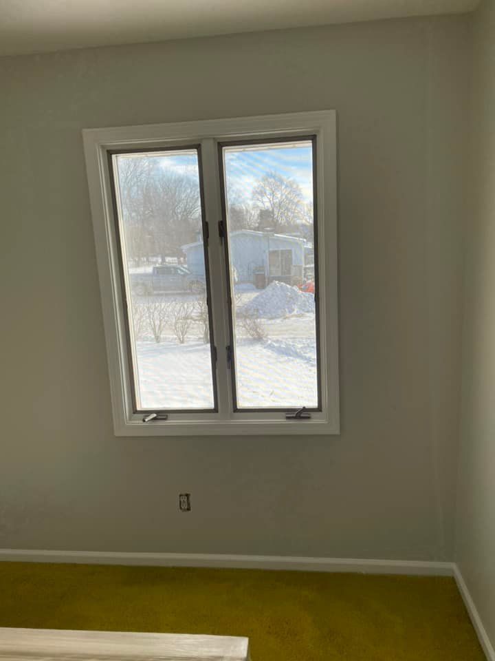 A bedroom with a window looking out to a snowy yard.