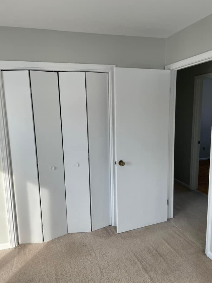 A room with a lot of white doors and a carpeted floor