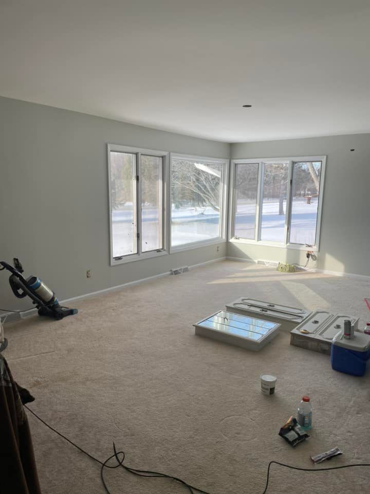 A living room with a lot of windows and a vacuum cleaner on the floor.