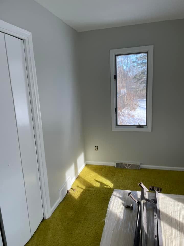 A room with a window and a yellow carpet.