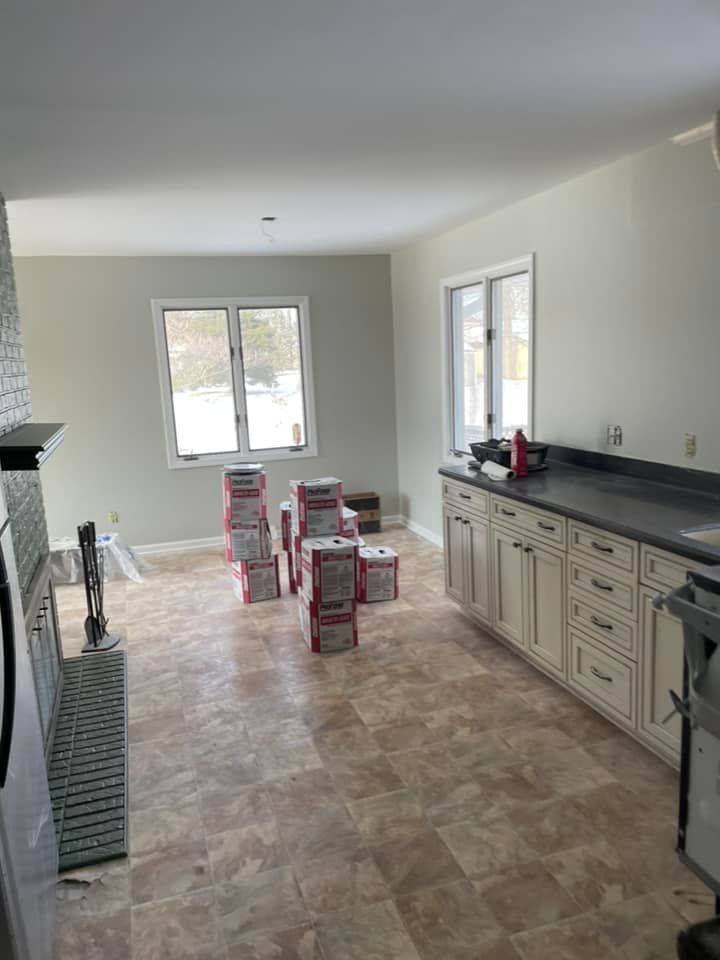 A kitchen with a lot of boxes of paint on the floor.