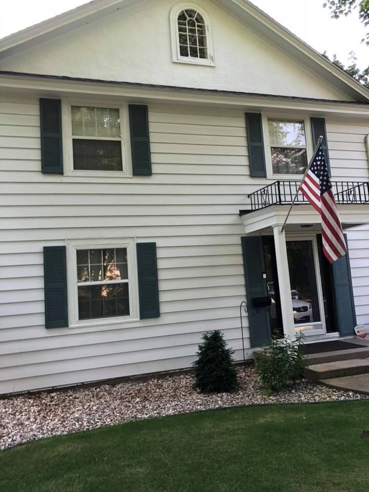 A white house with blue shutters and an american flag