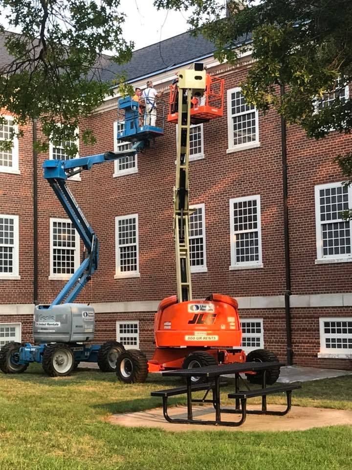 A man is painting a brick building with a crane.