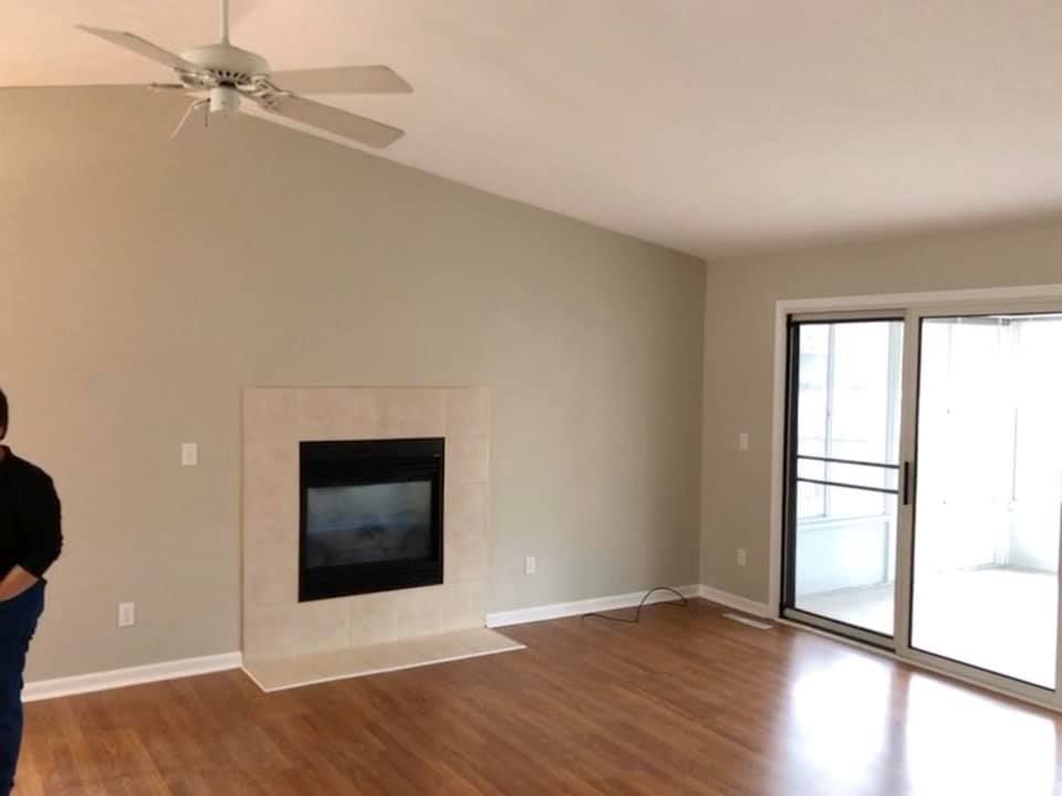 An empty living room with a fireplace and a ceiling fan