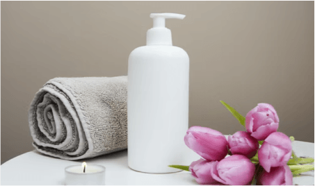 injury wellness centre. Image A bottle of lotion and a towel with a candle and flowers for a massage