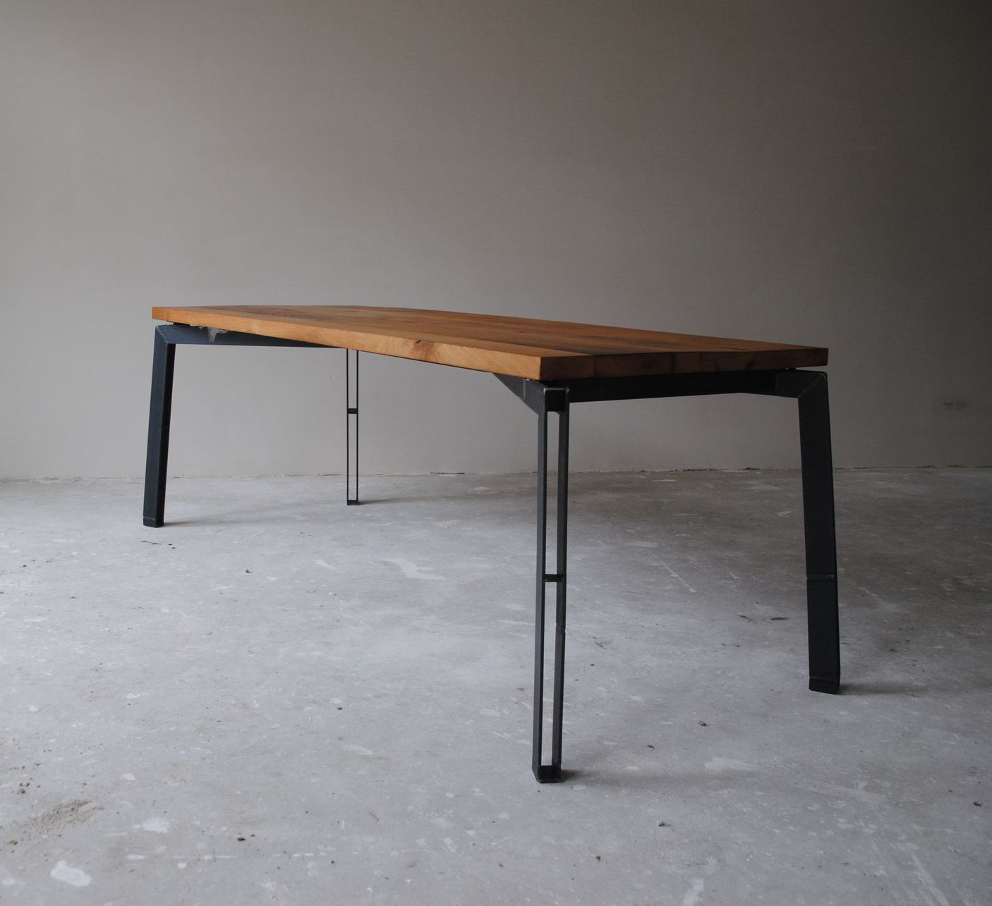 Een houten tafel met metalen poten staat op een betonnen vloer