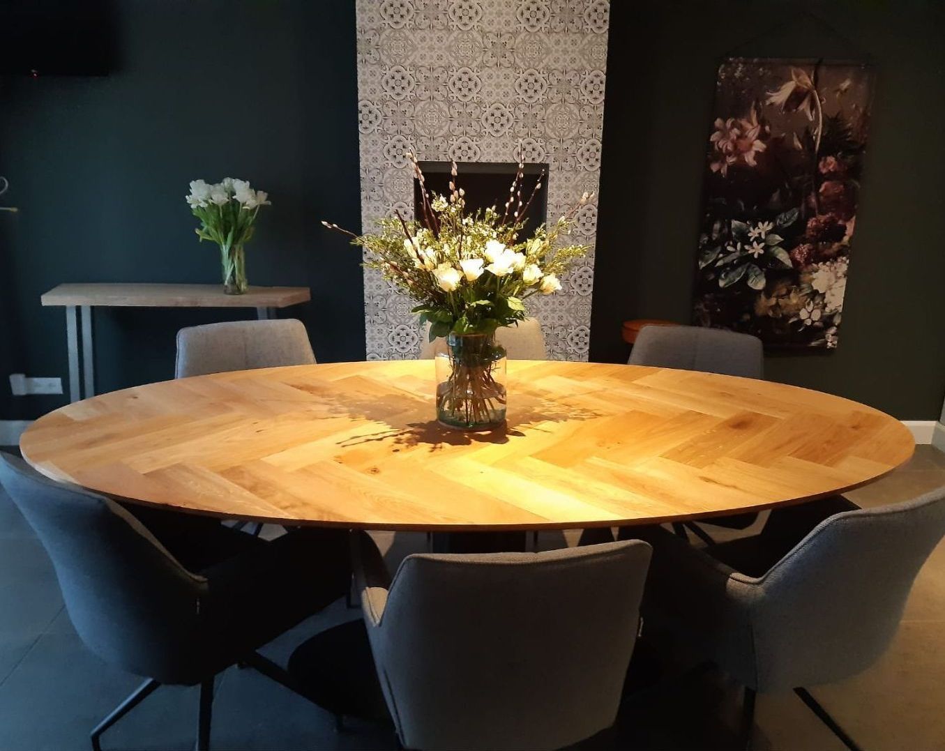 Een ronde houten tafel met een vaas met bloemen erop