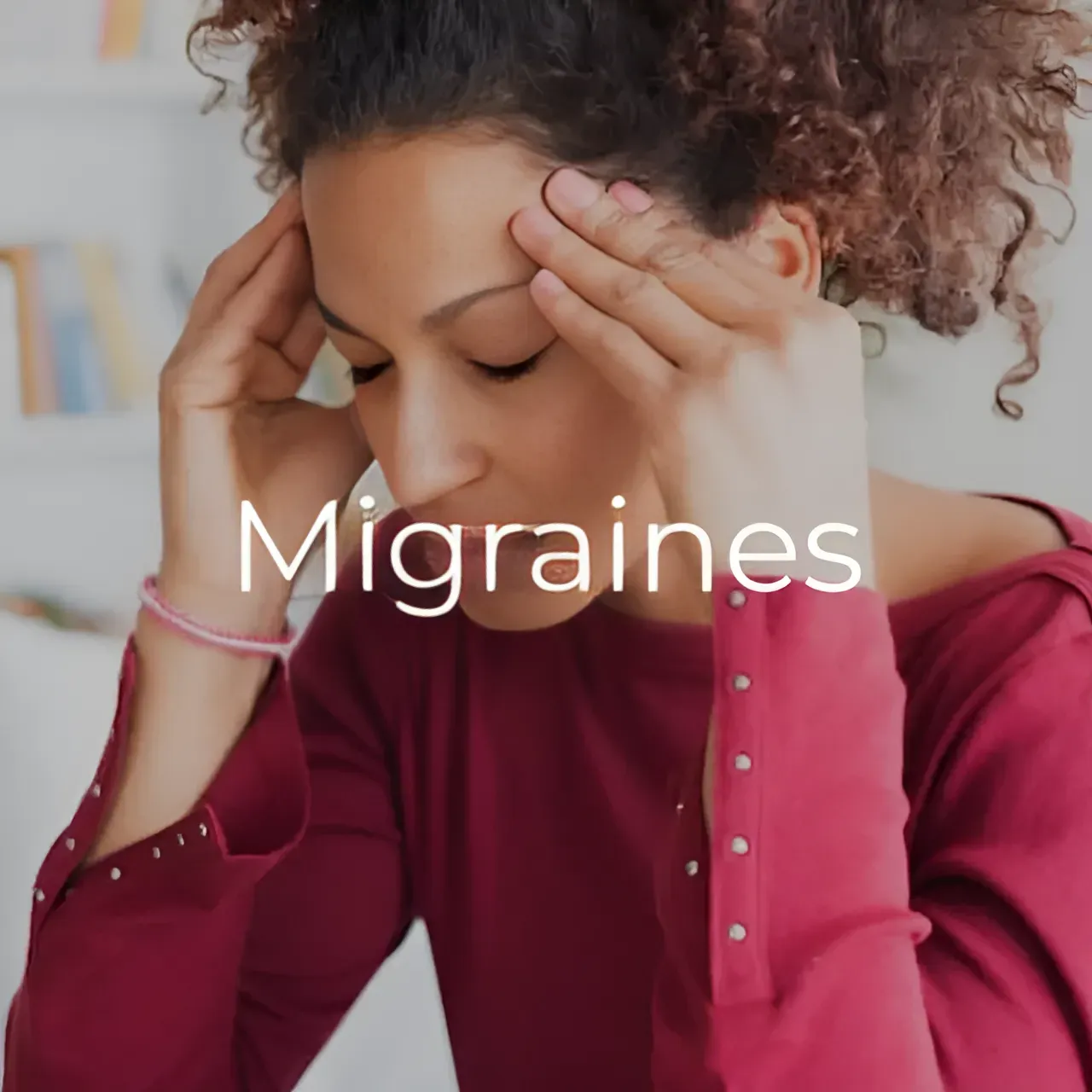 A woman is sitting on a couch with her hands on her head