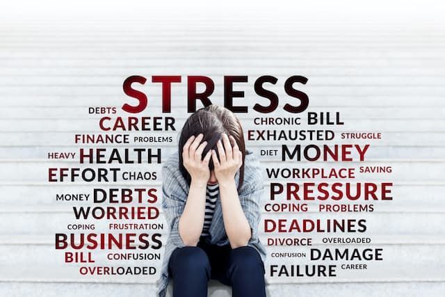 A woman is sitting in front of a wall with the word stress written on it