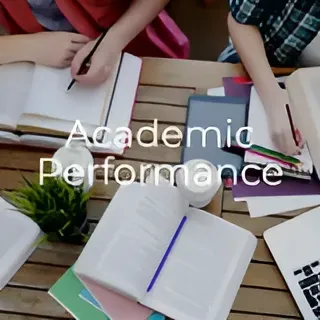 A group of people are sitting at a table with books and a laptop
