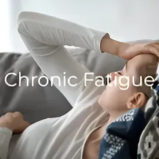 A woman is laying on a couch with a pillow on her head