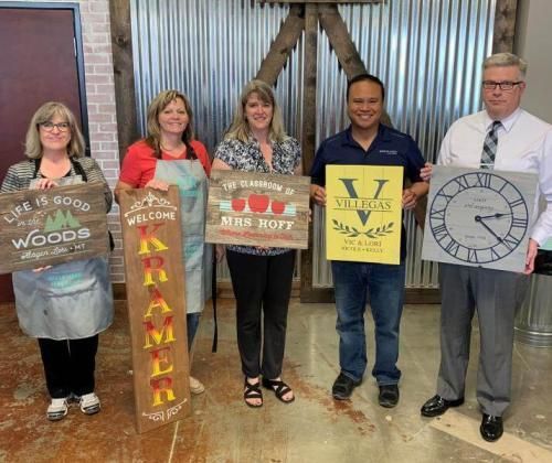 A group of people are standing next to each other holding signs and a clock.
