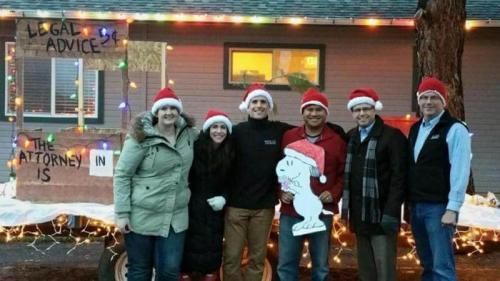 A group of people are standing in front of a house decorated for christmas.