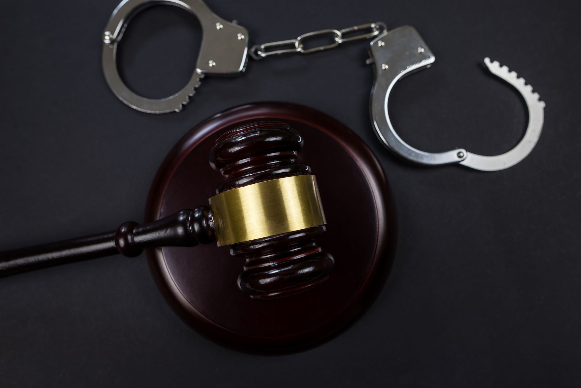 A judge 's gavel and handcuffs on a black background.