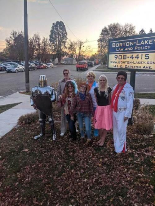 A group of people dressed in costumes are standing in front of a sign.