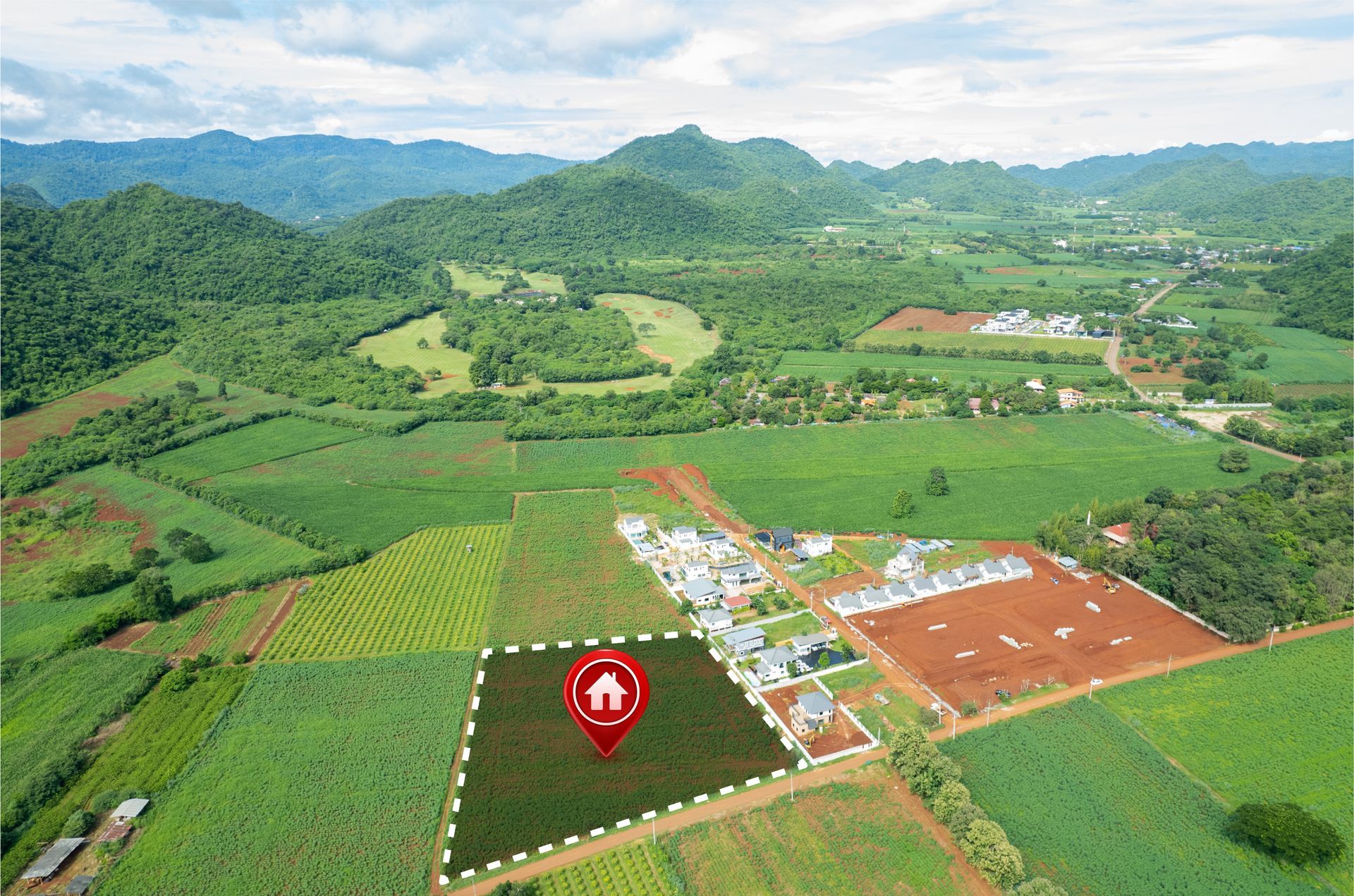 An aerial view of a lush green field with mountains in the background.