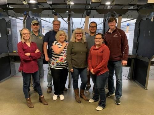 A group of people at an indoor firing range.