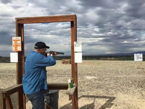 A man shooting a shotgun at a target.