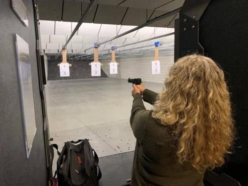 A woman shooting a handgun at a firing range.