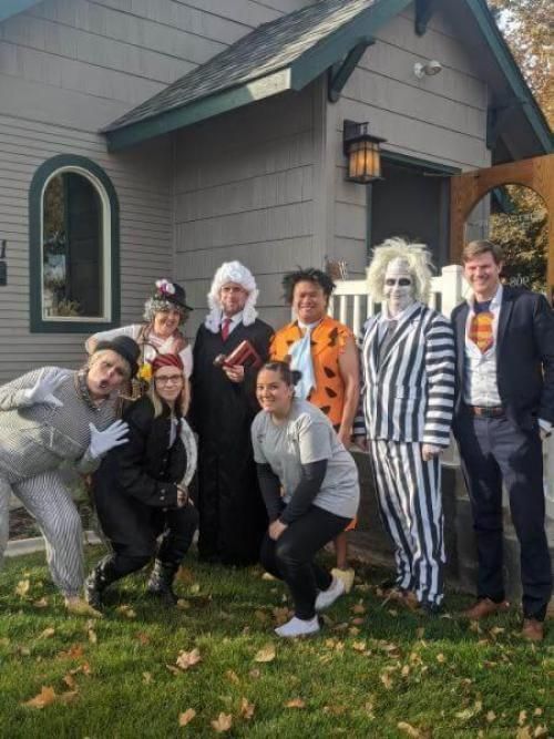 A group of people in costumes are posing for a picture in front of a house.