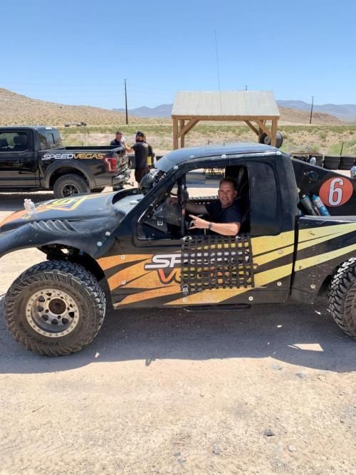 A man is sitting in a truck with the number 6 on the back.