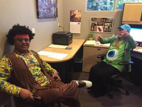 A man in a hippie costume sits next to a woman in a green eye costume
