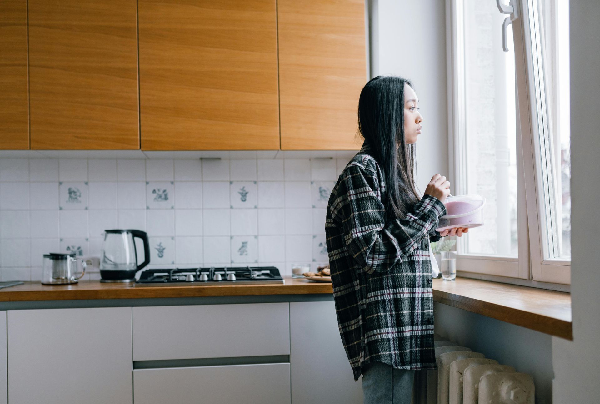 Woman looking out window while eating snack