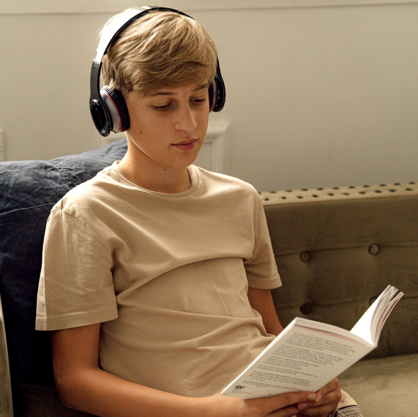A young boy wearing headphones is reading a book