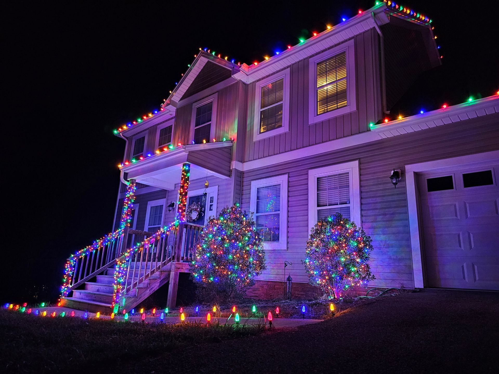 House decorated with colorful Christmas lights at night.