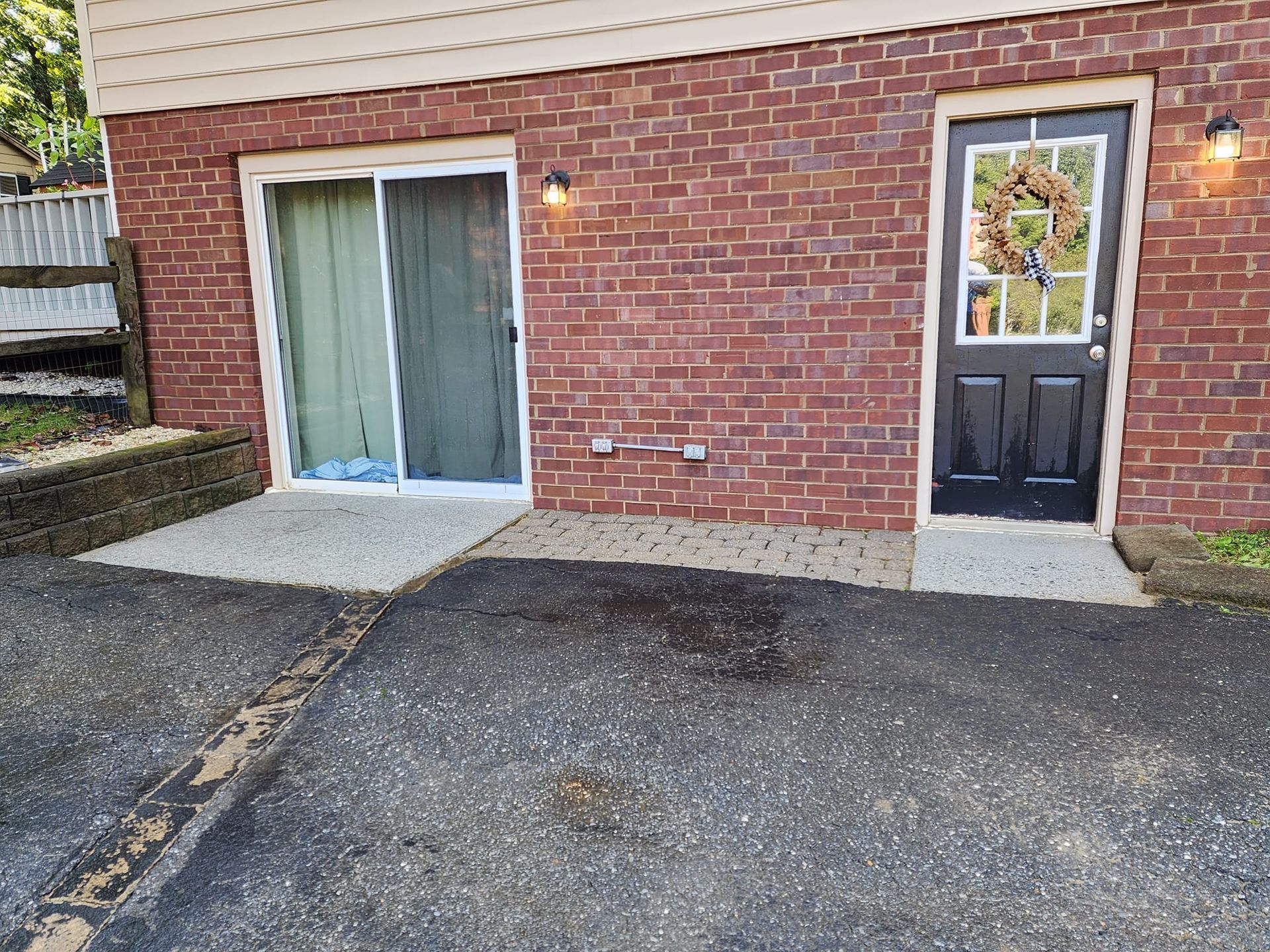 Exterior view of a brick building with a sliding door, a black door, and concrete pathways.
