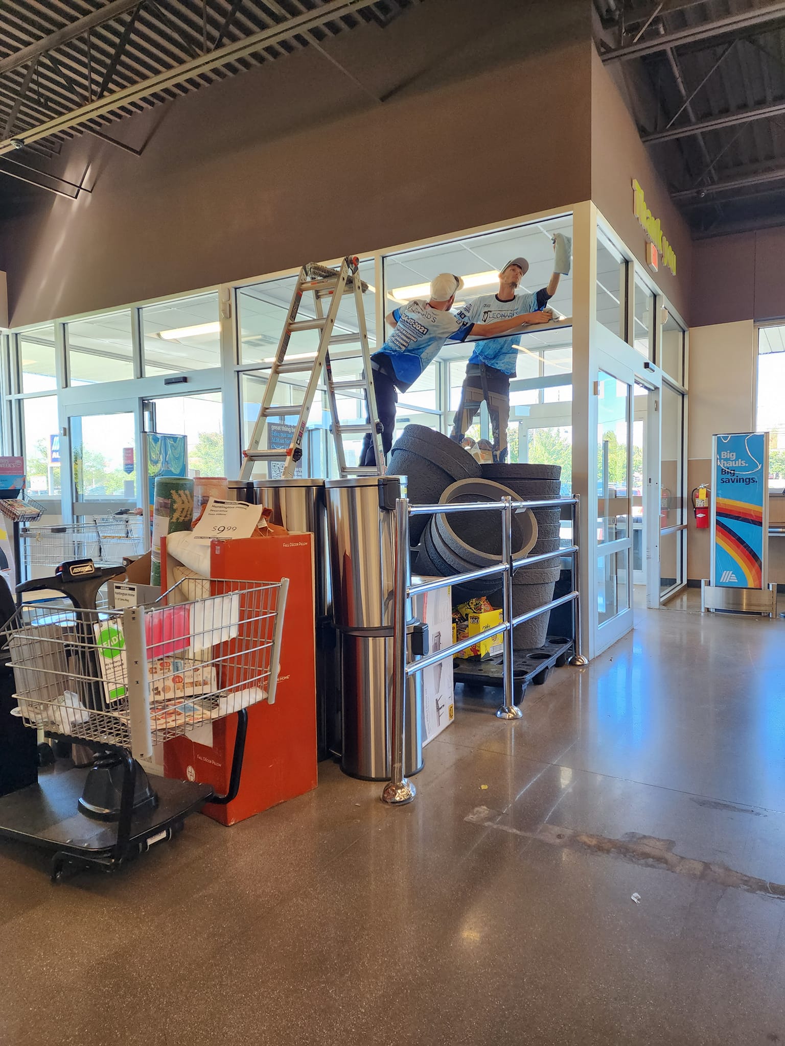 Two people on tires by a building, one on a ladder.