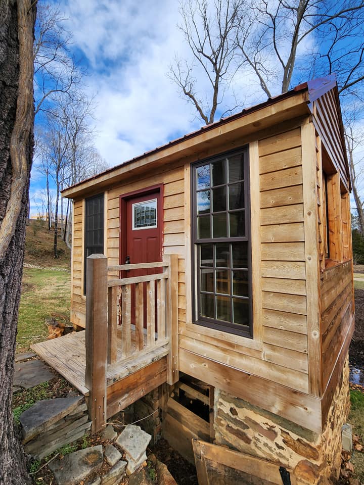 Small wooden cabin with red door, brown window, and wooden porch.