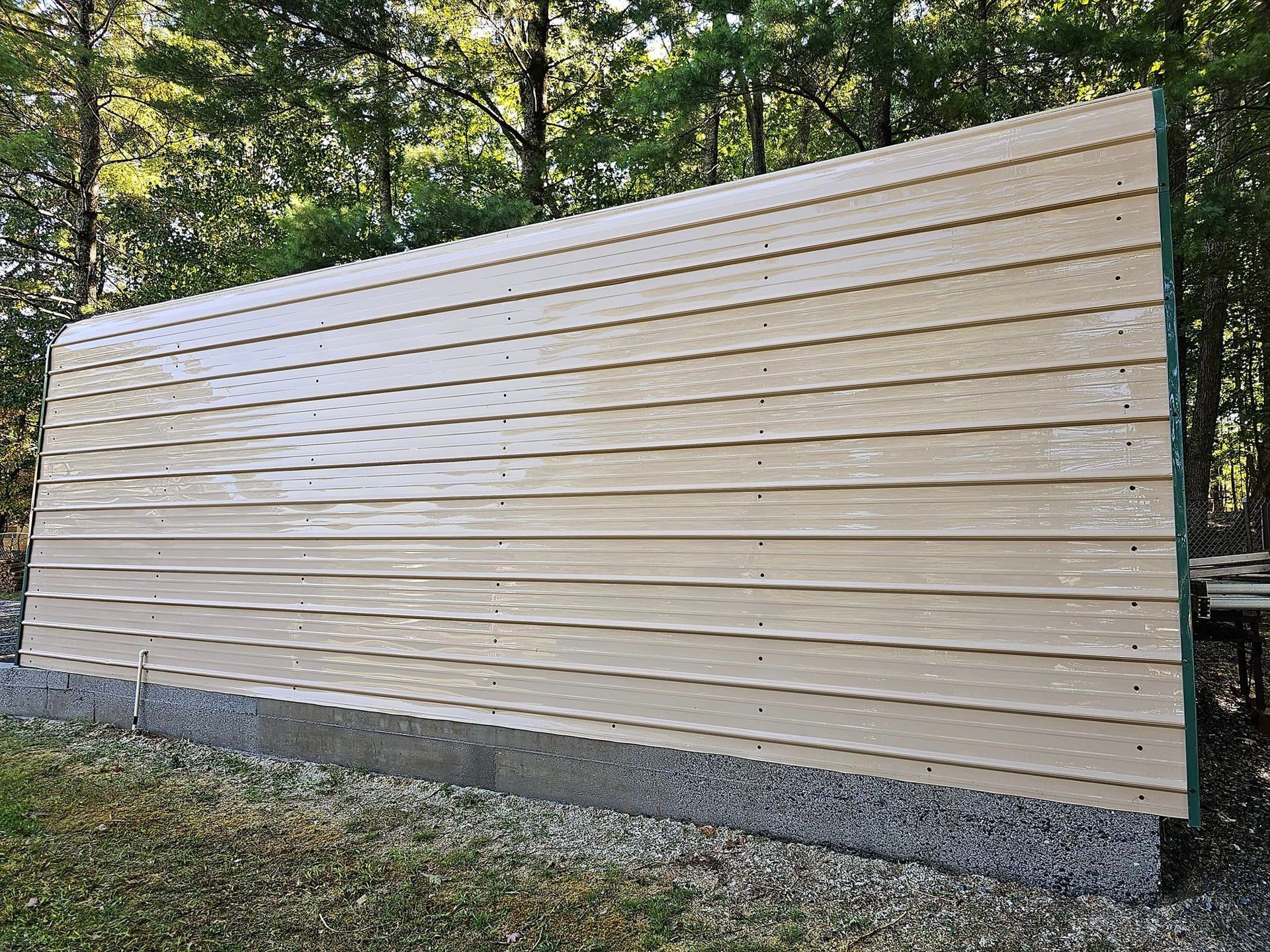 Tan siding on a concrete base, set against a backdrop of trees.
