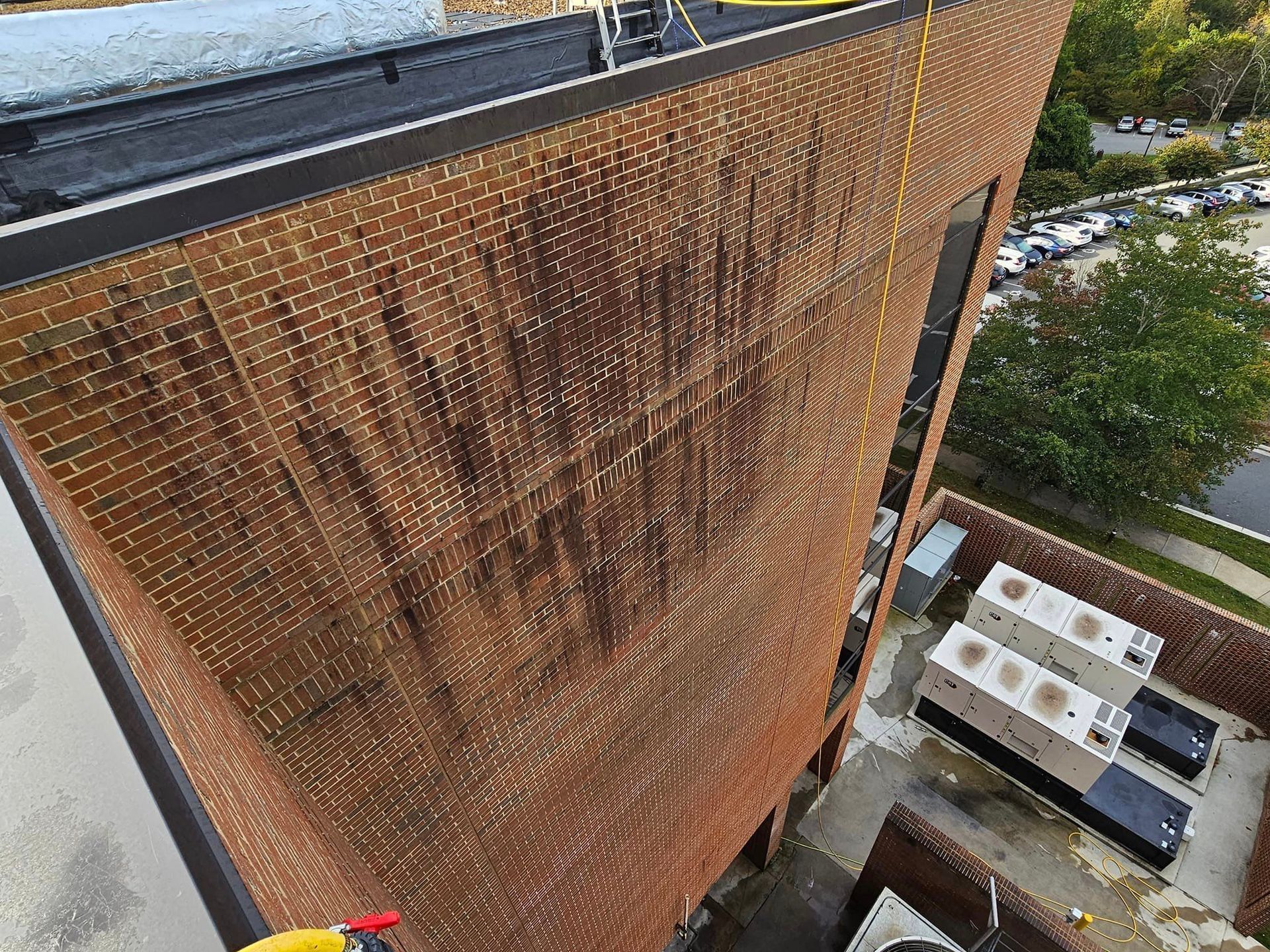 Tall brick building with dark staining, viewed from above. Rooftop and equipment visible.