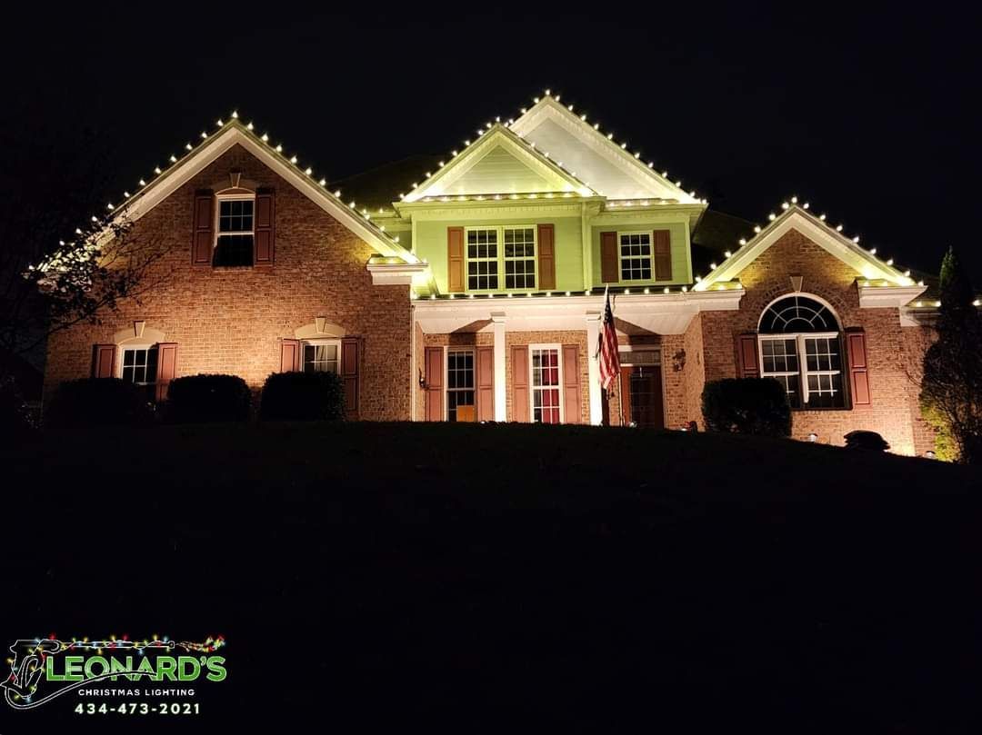 A house at night, lit with Christmas lights around the roof and illuminated facade.
