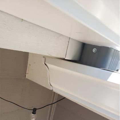 White and beige trim and guttering with a grey downspout attached to a building.