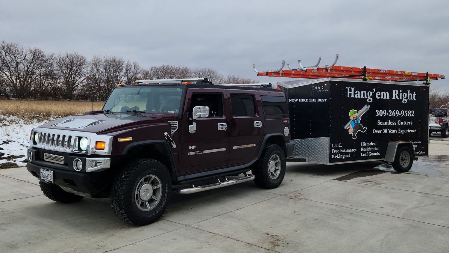 Dark red Hummer towing a trailer with 