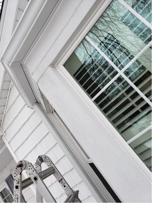White house exterior with window, gutter, and ladder.