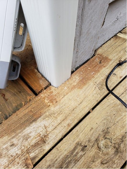 Wooden deck with white gutter and post, possibly showing signs of rot.