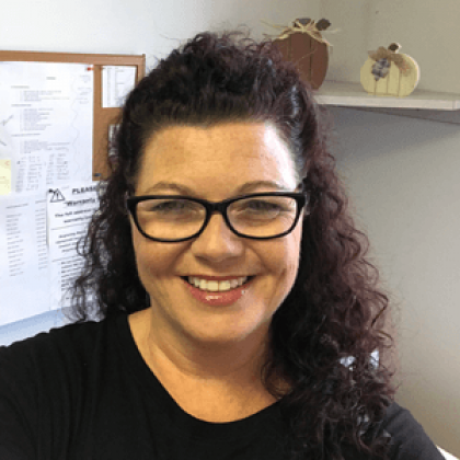 A woman wearing glasses and a black shirt smiles for the camera
