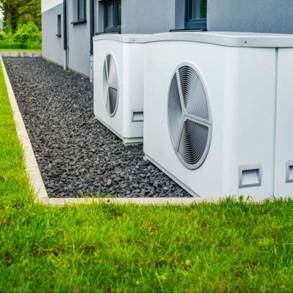 Two air conditioners are sitting next to each other on the side of a building.