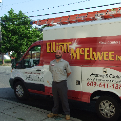 A man stands in front of an Elliott-Mcelwee heating and cooling van