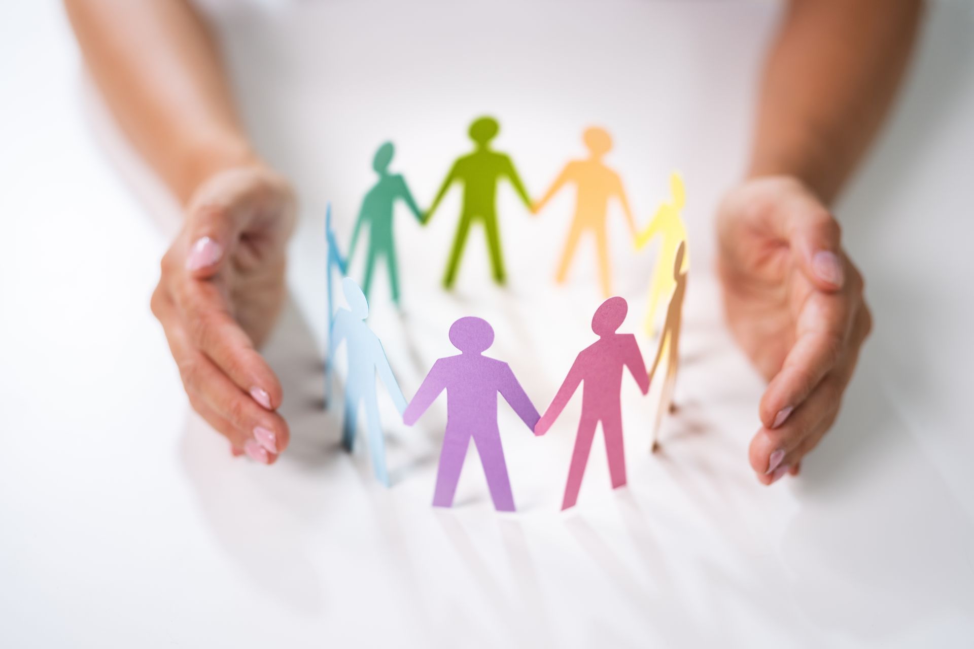 a woman holds a circle of paper people holding hands