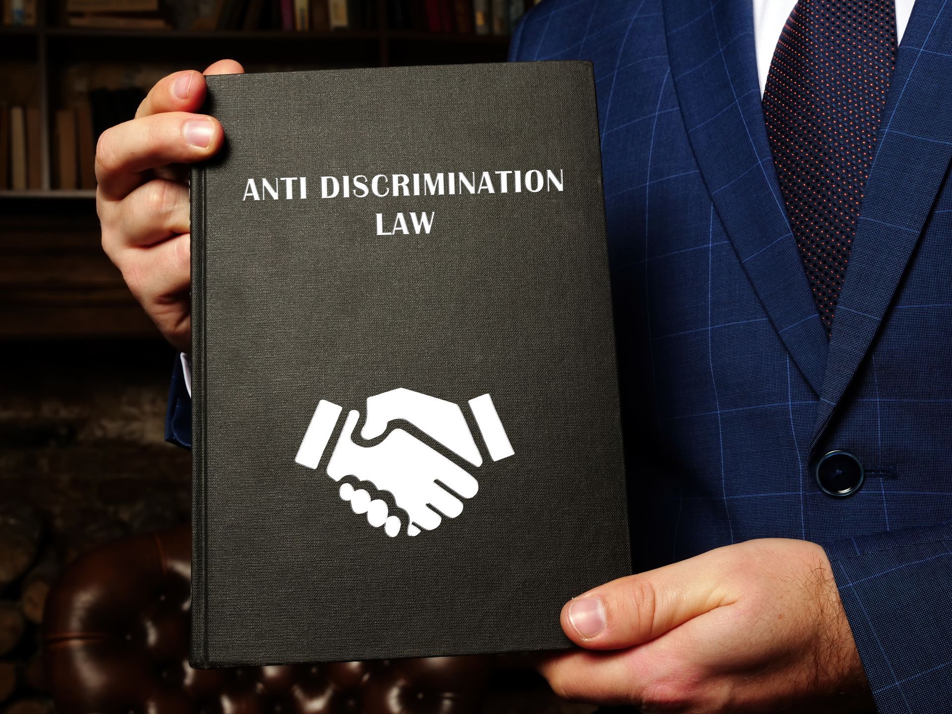 a man in a suit is holding a book titled anti discrimination law