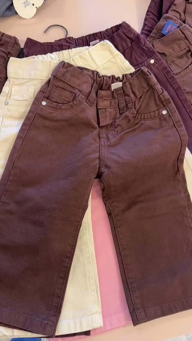 Pantalones infantiles de color marrón y crema, apilados.