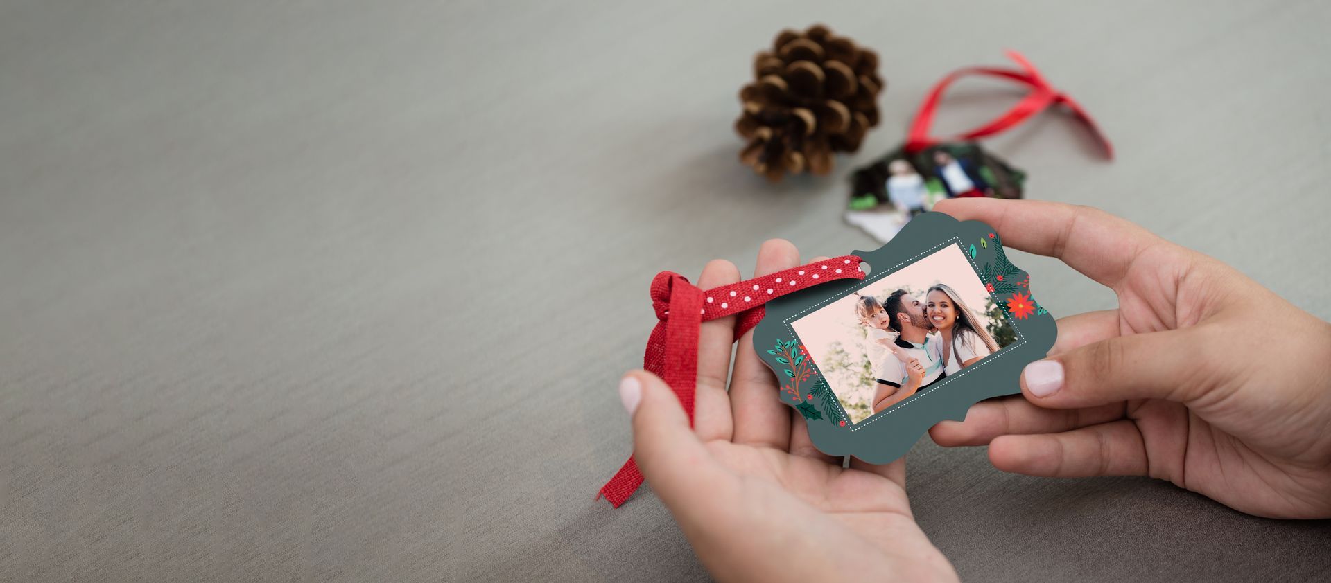 Pair of hands holding a custom photo ornament with red ribbon hanger