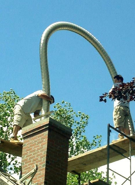 Two Men Installing the Chimney Steel Liner – West Springfield, MA – Rolandini Brothers Masonry